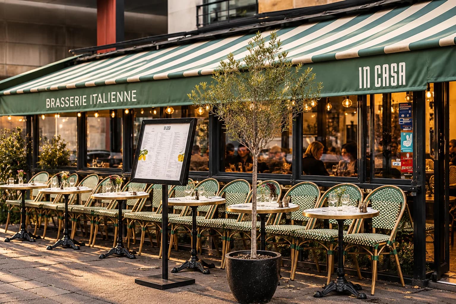 Terrasse d’In Casa, chaises rotins vertes et store rayé, sur la rue Desaix.